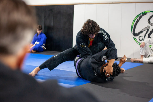 BJJ practitioner watching training from the mat's edge