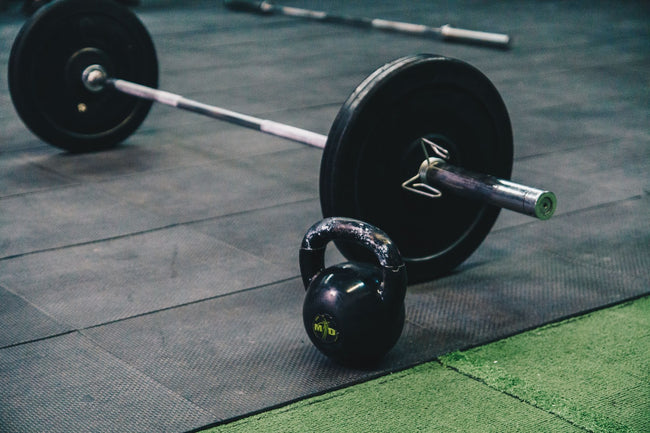 Barbell and kettlebell on a gym floor